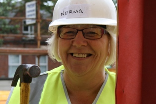 A local Habitat volunteer (Norma) smiling to camera while holding a hammer