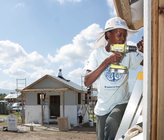 A Habitat volunteer holding a drill, working on site in Haiti