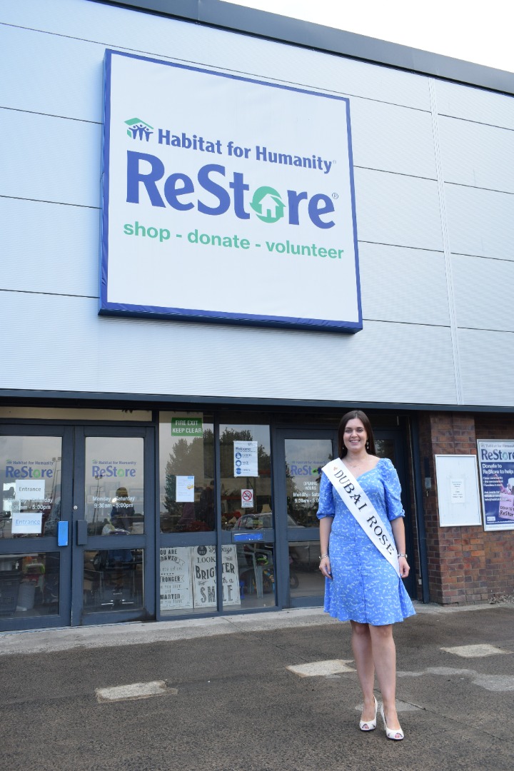 Dubai Rose, Aileen McAlister, standing in front of ReStore Ballymena, wearing a blue dress and her white competition sash